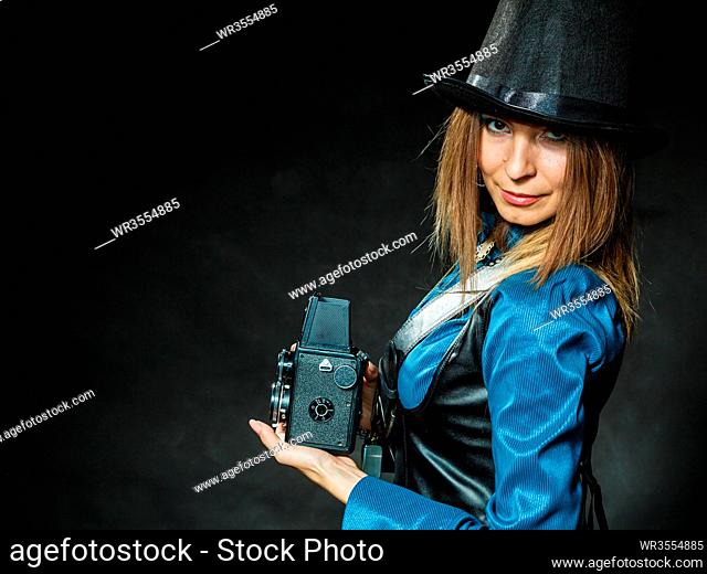 Photography and retro style. Young vintage attractive girl holds old aged camera. Steampunk photographer taking photo
