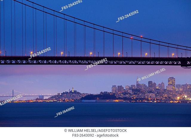 San Francisco, CA, USA: city skyline, Golden Gate Bridge, Bay Bridge, Coit Tower, Fisherman's Wharf, high-rise office buildings, dusk, view from Kirby Cove