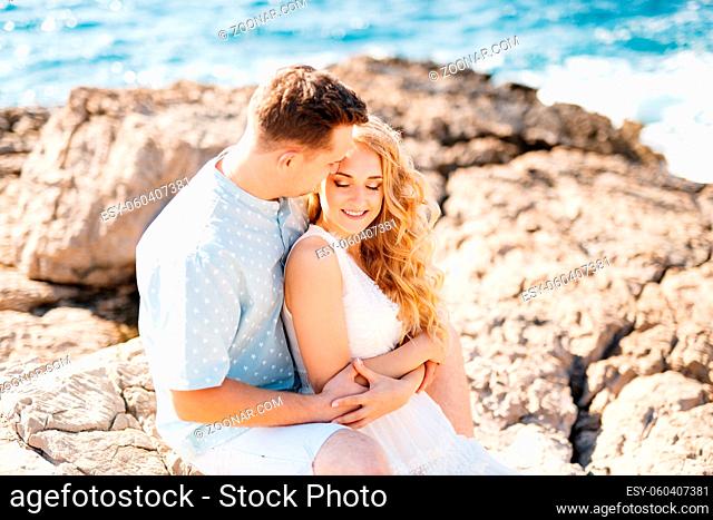 Man and woman in love embracing, smiling and holding hands on the rocky seashore . High quality photo