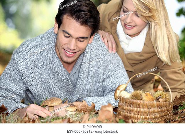 Couple with basket full of mushrooms and chestnuts