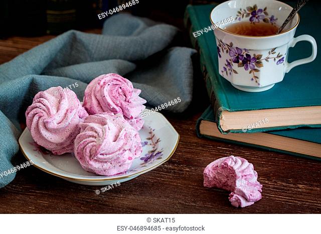 Homemade marshmallow or zephyr with a cup of tea over the wooden background