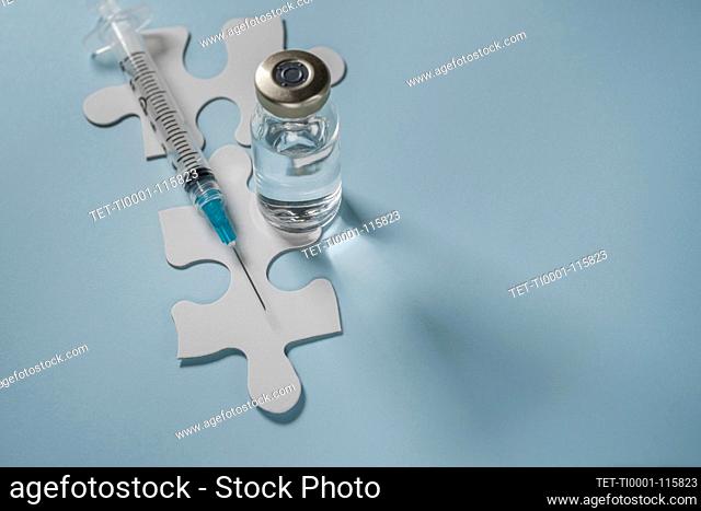 Vial of Covid-19 vaccine and syringe on jigsaw puzzles
