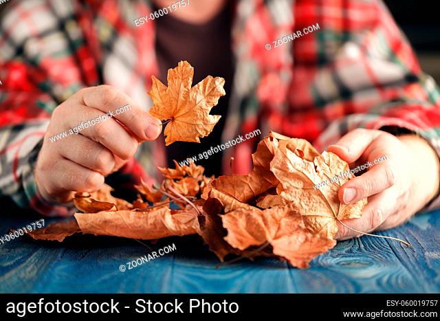 male hands playing with dry leaves, close up view