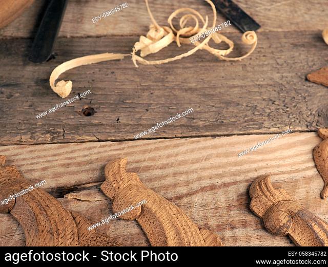 Carved oak decorative elements on a rustic workbench with chisels, text free space in the center, wood working or creativity concept
