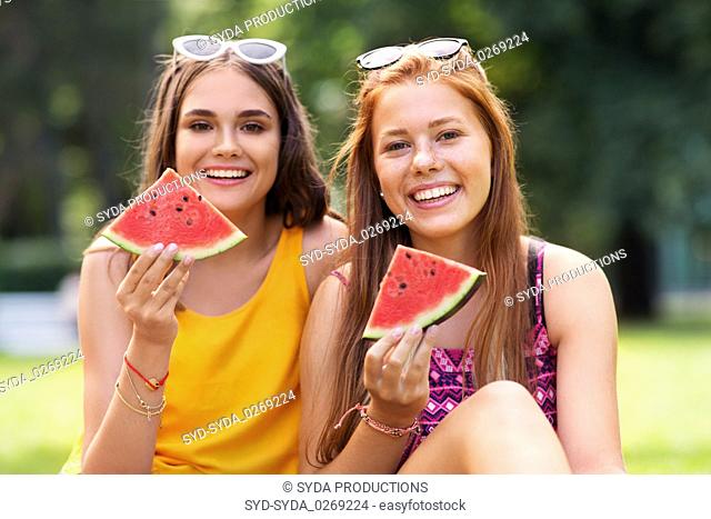 teenage girls eating watermelon at picnic in park