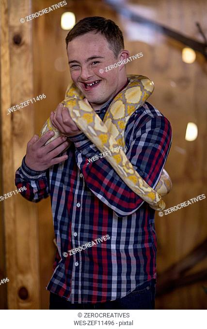 Young man with down syndrome holding albino python snake