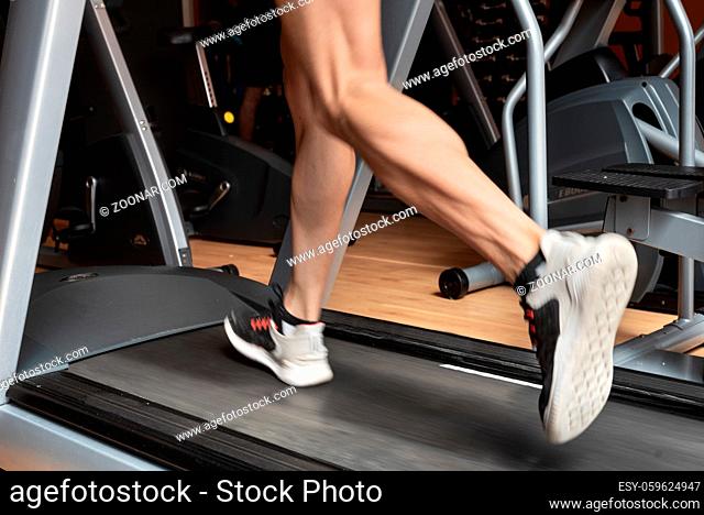 Man running in a gym on a treadmill concept for exercising, fitness and healthy lifestyle