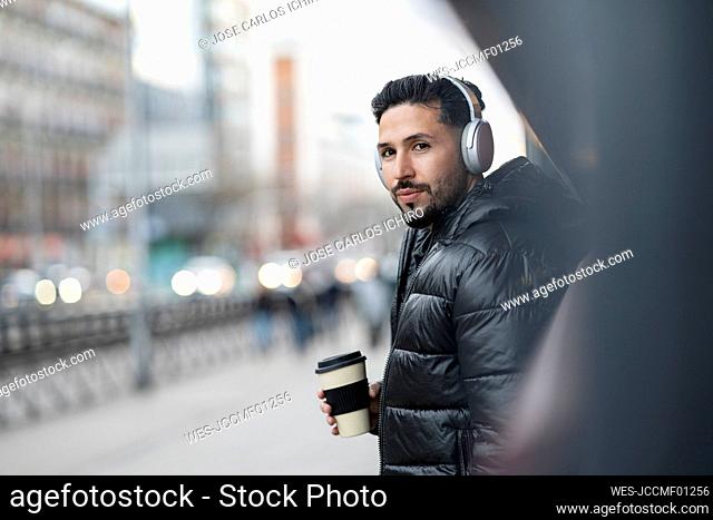 Handsome man with headphones holding coffee cup