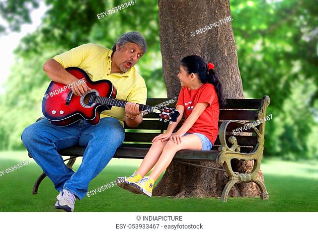 Grandfather playing the guitar for granddaughter