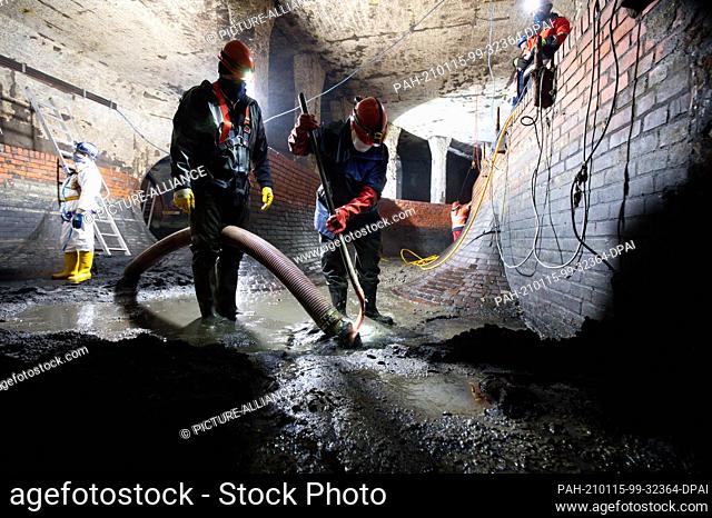 14 January 2021, Hamburg: Sewer workers use shovels and suction hoses to clean the strainer junction structure at the Hafenstraße pumping station