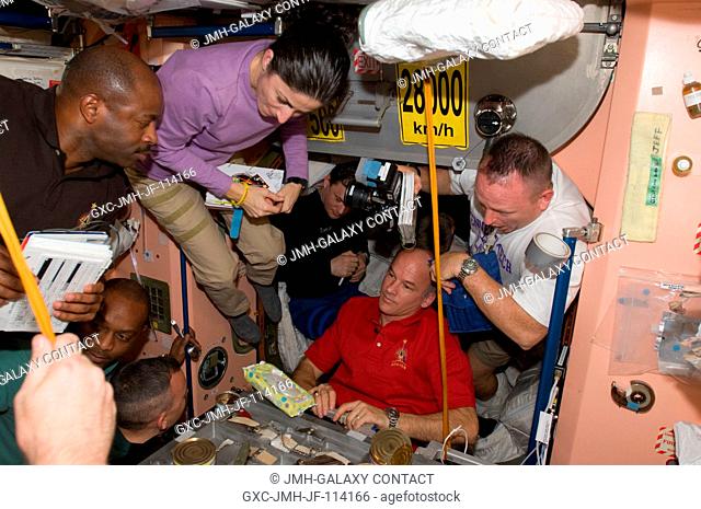 Expedition 21 and STS-129 crew members gather for a meal at the galley in the Unity node of the International Space Station while space shuttle Atlantis remains...