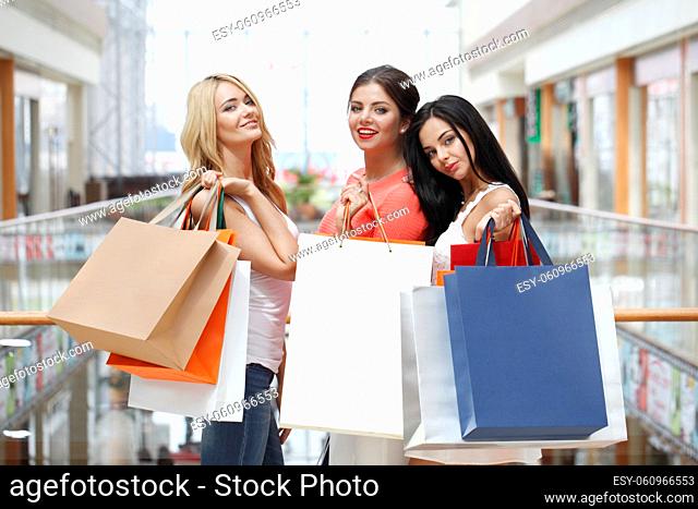 Young beautiful happy girls showing shopping purchase bags in mall