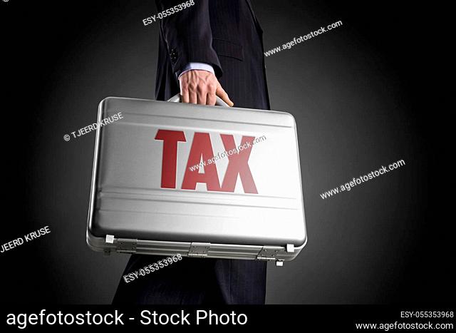Businessman with suitcase with letters TAX on a dark background with circle gradient