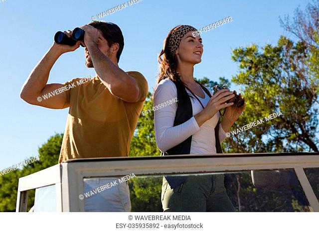 Couple using binoculars in off road vehicle