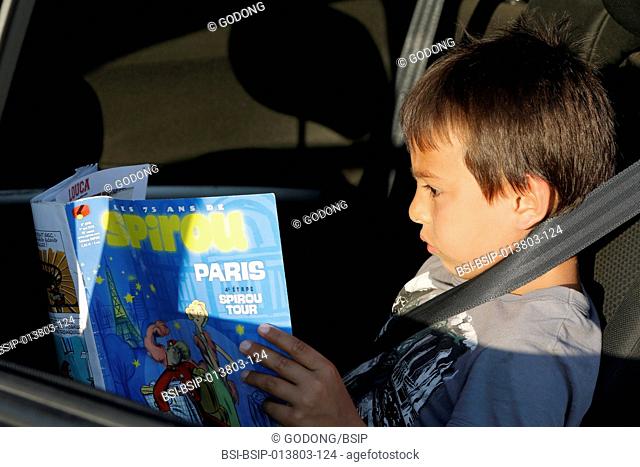 7-year-old boy reading a magazine in a car