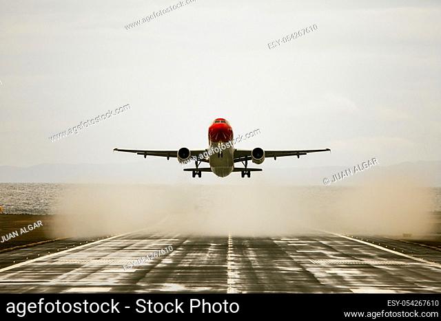 Plane with red cockpit is about to land. Horizontal outdoors shot