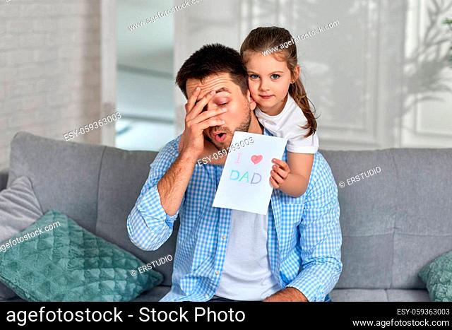 cute child daughter congratulates her father and gives him greeting card. Dad and little girl smile and hug. father's day