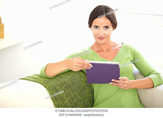 Caucasian young woman in a green shirt looking at the camera while holding a tablet - copy space