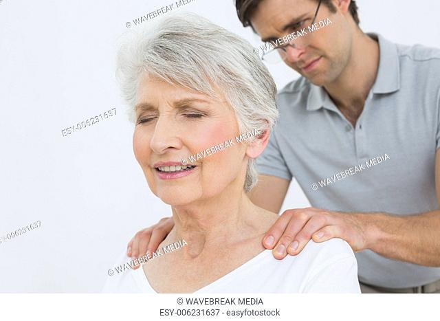 Male physiotherapist massaging a senior woman's neck