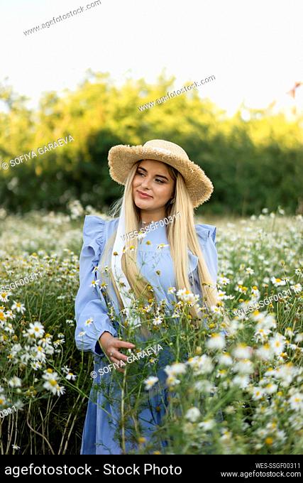 Thoughtful woman holding flowers in meadow
