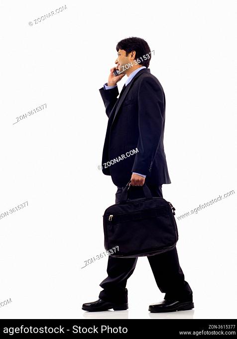 Side view of a happy Indian business man talking on the mobile phone isolated over white background