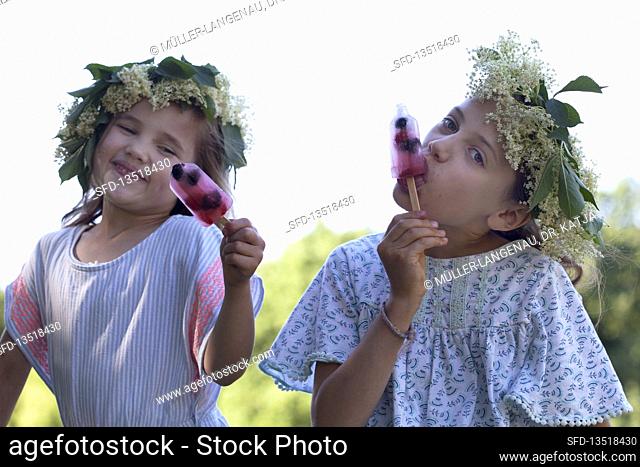 Girls with flower wreaths eating popsicles