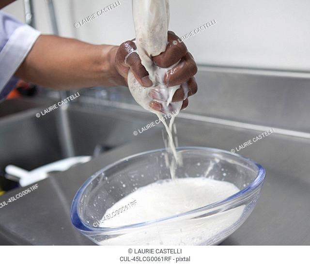 Man wringing almond milk from cheesecloth