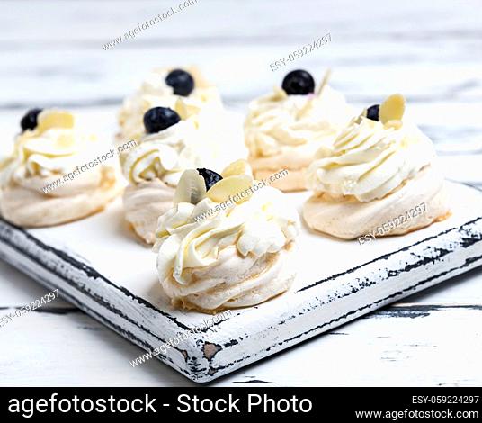 small baked round cake meringue with whipped cream on a white wooden board