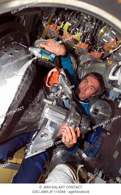 Cosmonaut Sergei K. Krikalev, Expedition 11 commander representing Russia's Federal Space Agency, dismantles the probe-and-cone docking mechanism in the...