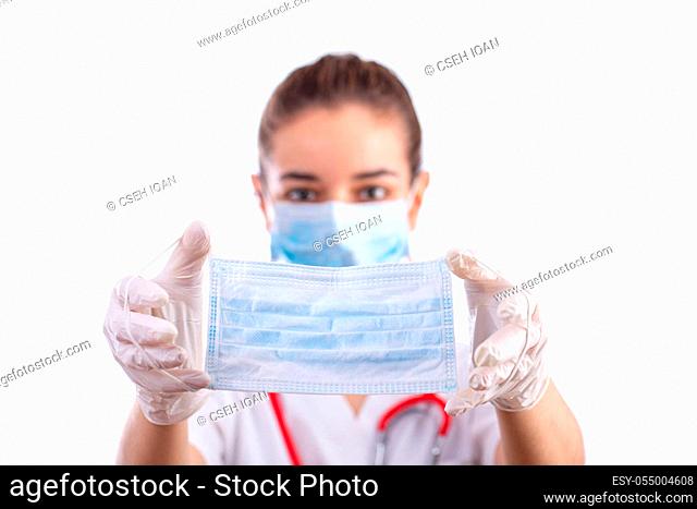Young female doctor with face mask giving single use protective mask. Selective focus