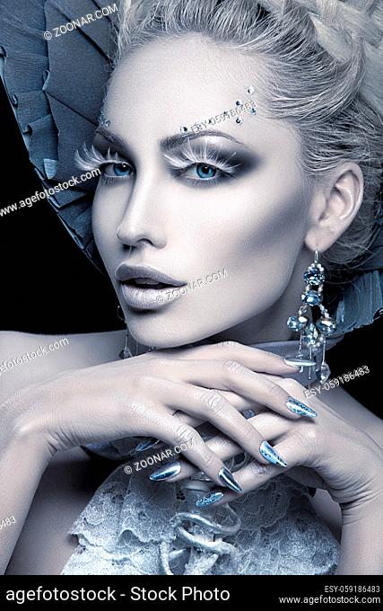 Closeup portrait of beautiful young woman dressed as winter queen. Creative makeup. Over black background. Copy space