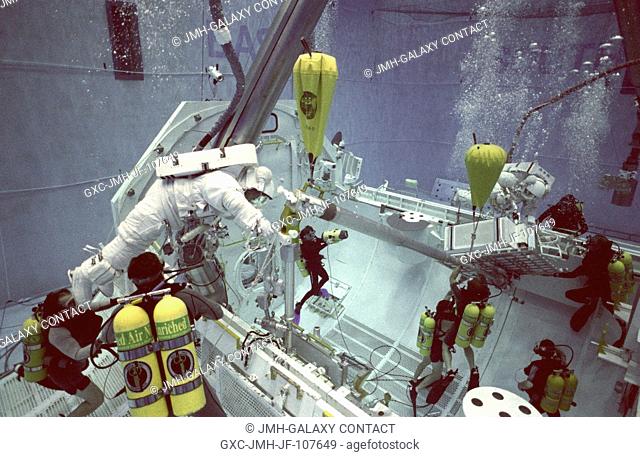 Wearing training versions of the Extravehicular Mobility Units (EMU), astronauts Takao Doi and Winston E. Scott participate in an underwater simulation of a...