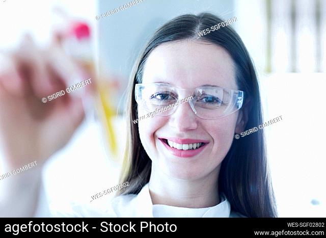 Smiling female scientist holding test tube in laboratory