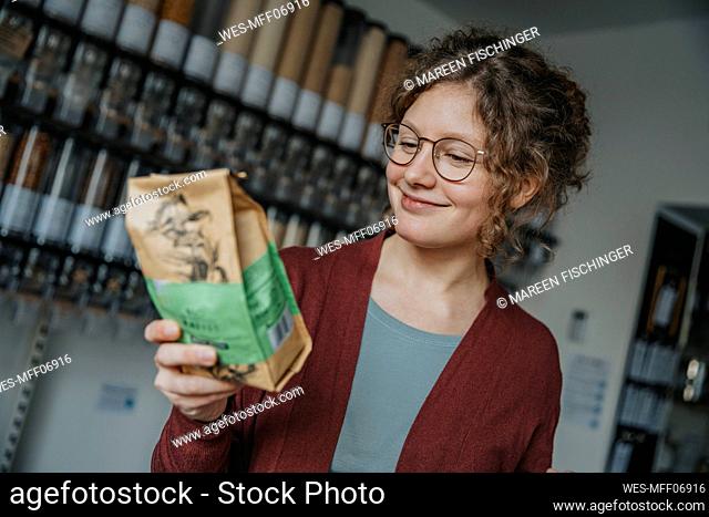 Smiling young woman reading label on package in zero waste shop