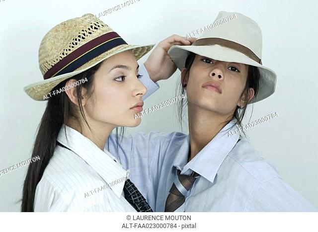 Two young female friends dressed in button down shirts, ties and hats, portrait