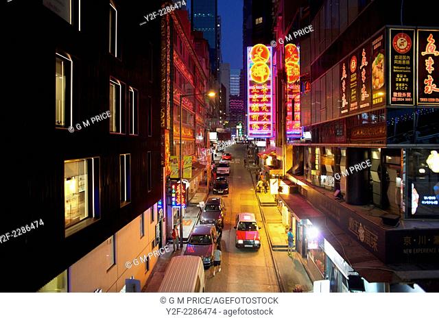 elevated view of taxi driving through neon lit restaurants and shops in Soho district, Hong Kong