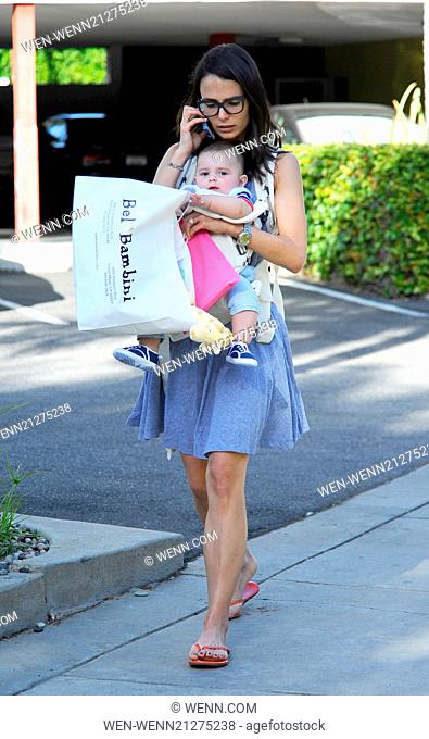 Jordana Brewster out and about talking on her cell phone as she has a handful multi-tasking carrying her son Julian in a sling and a shopping bag of toys from...