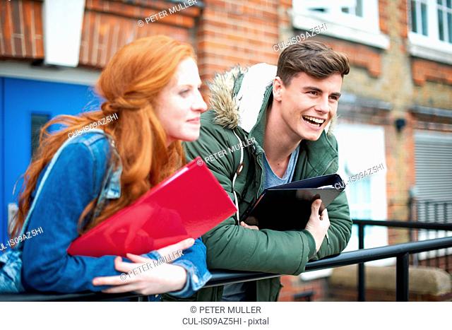 Young college student couple leaning against campus handrail