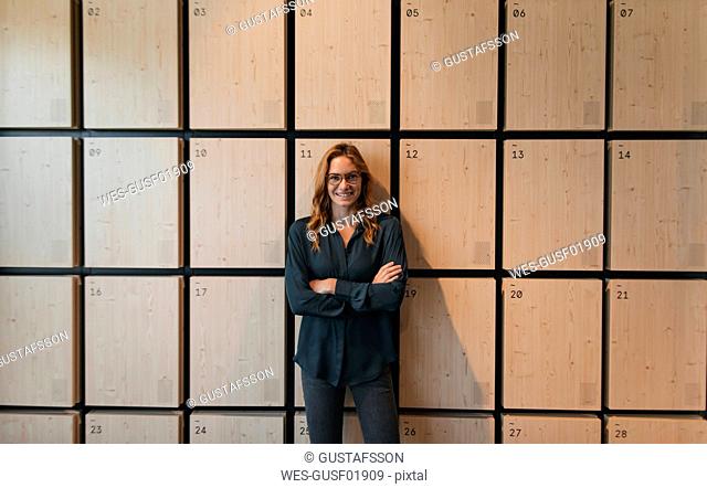 Portrait of smiling businesswoman standing at lockers