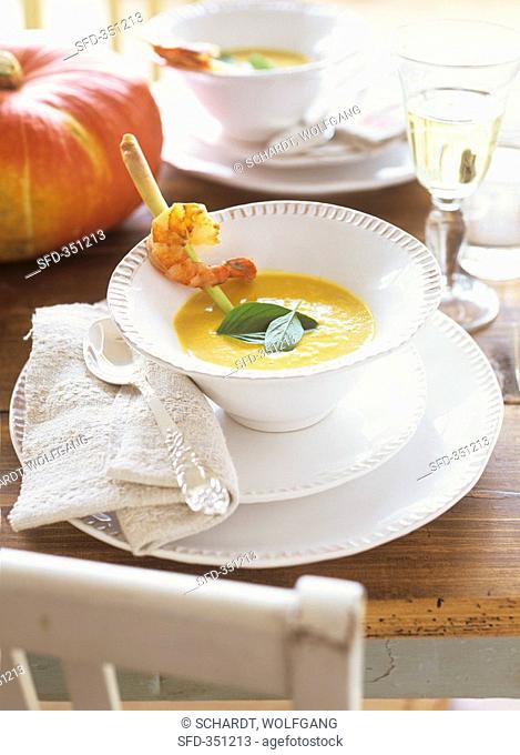 Pumpkin & coconut soup garnished with prawn on lemon grass