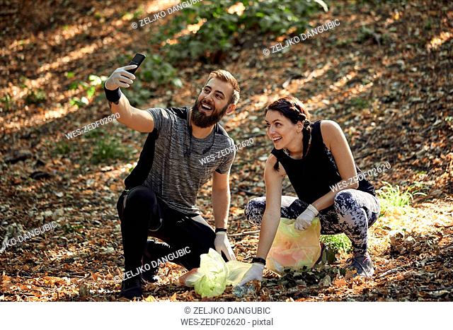 Couple taking a selfie during plogging in forest