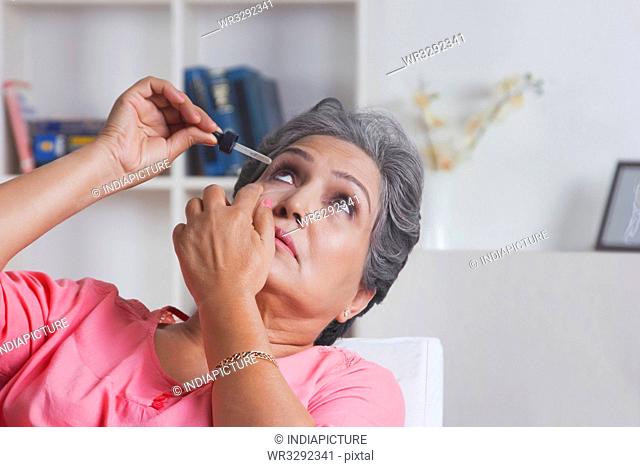 Old woman putting eye drops