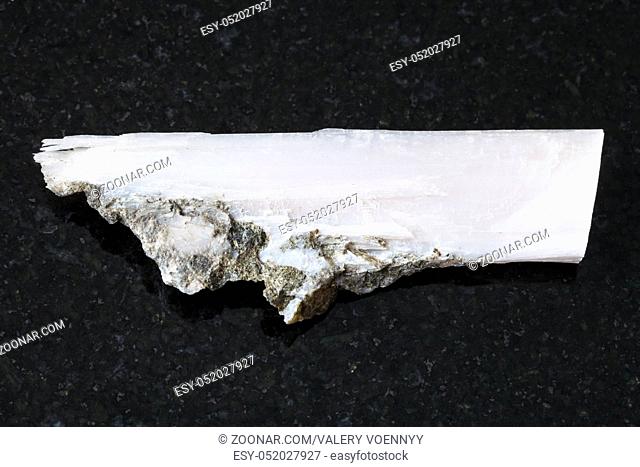 macro shooting of natural mineral rock specimen - rough crystal of xonotlite gemstone on dark granite background from Norilsk district, Russia