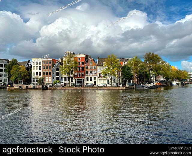 Amsterdam, Netherlands - October 2, 2019: Amsterdam canal with typical dutch houses and houseboats, boats in the evening with beautiful water reflections