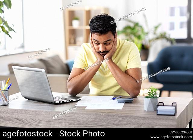 man with calculator and papers working at home