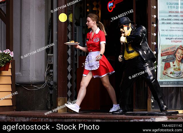 RUSSIA, MOSCOW - JULY 3, 2023: A waitress is seen by a cafe in Arbat Street. Artyom Geodakyan/TASS
