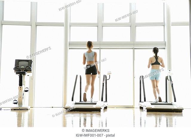 Two young women on walker as they exercise in a well equipped gym