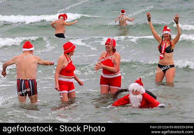 24 December 2020, Mecklenburg-Western Pomerania, Warnemünde: Decorated for Christmas, members of the Rostock Seal Club go swimming in the 6