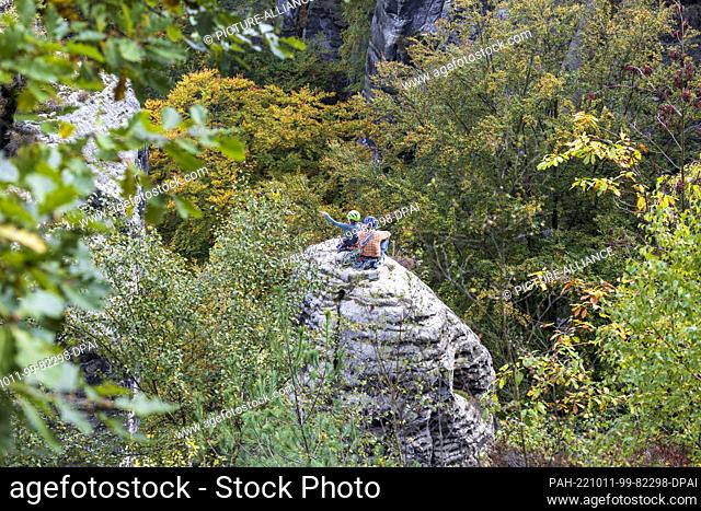 10 October 2022, Saxony, Lohmen: Two climbers are sitting on a sand monolith at the Bastei. The rocks of Saxon Switzerland are very sought-after climbing...