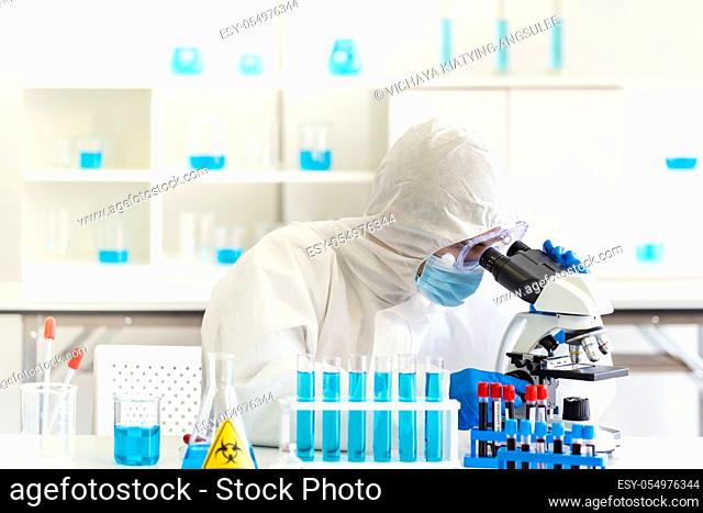 Young asian scientist doing some research and looking through a microscope in a laboratory to study about coronavirus COVID-19 to develope vaccine for 2019-ncov...